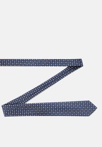 Granatowy krawat z powtarzającym się wzorem geometrycznym. Wykonany z gładkiego materiału, z zakończeniem w kształcie szpicy i wąską sylwetką.