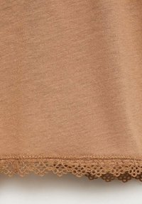 Bruine katoenen top met een gladde textuur. De zoom heeft een delicate kantafwerking, wat een decoratieve touch aan het ontwerp toevoegt.