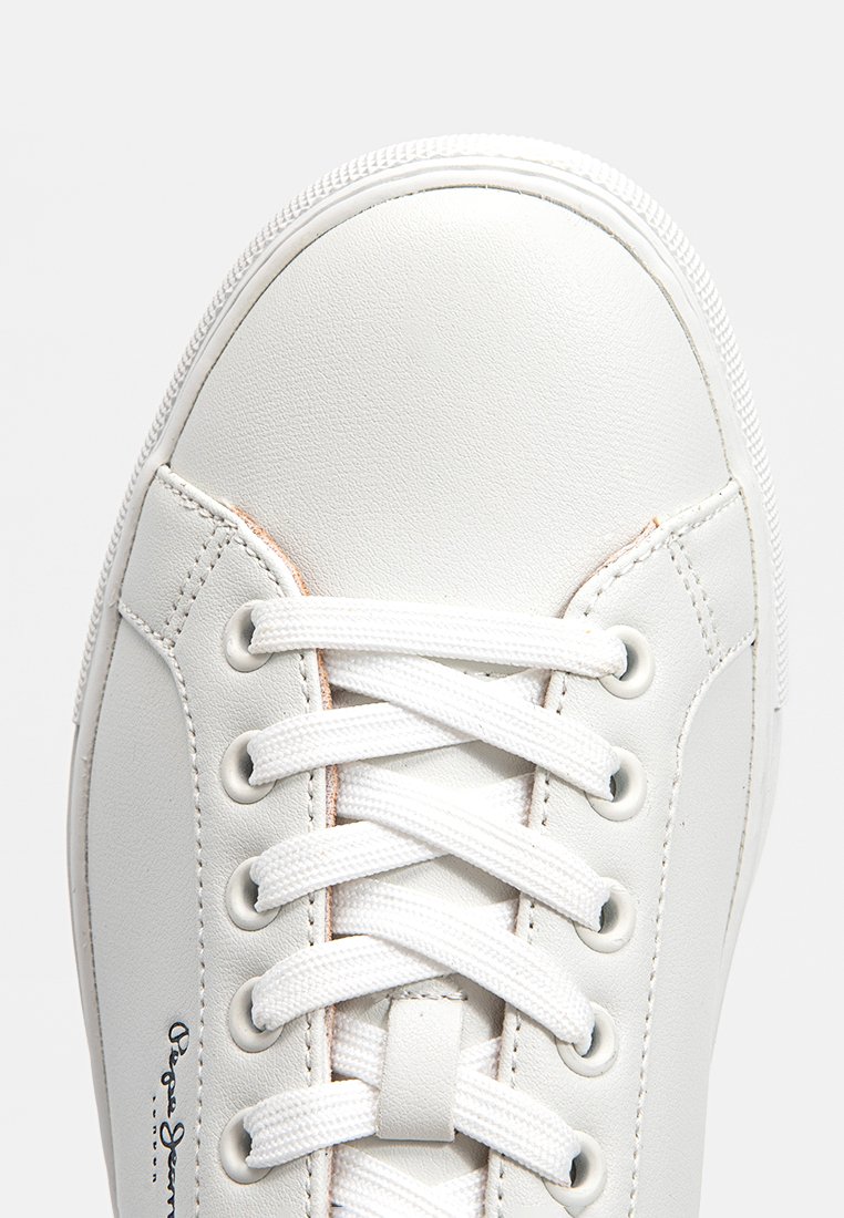 Sneaker en cuir blanc avec un bout arrondi, un design à lacets plats blancs et des détails de couture subtils. Présente une surface texturée et un branding minimal.