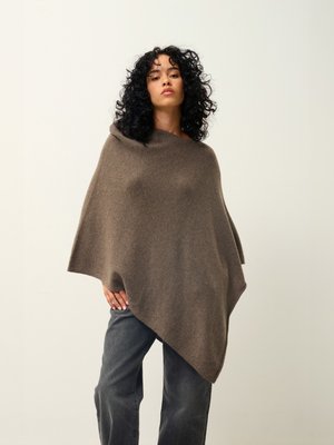Poncho en laine marron au design drapé, avec une texture douce et un ourlet asymétrique. Associé à un pantalon large gris.