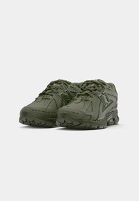 Baskets de sport vert olive avec des panneaux en maille, une languette rembourrée et des semelles amortissantes. Caractéristiques : accents texturés et logo proéminent sur les côtés.