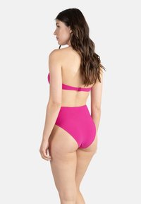 Bikini rose vif avec un col licou et une fermeture à agrafe à l'arrière. Bas taille haute avec une texture lisse et un design à couverture minimale.