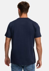 Camiseta de cuello redondo en azul marino con mangas cortas, hecha de algodón, que presenta una textura suave y un detalle de yugo trasero redondeado.