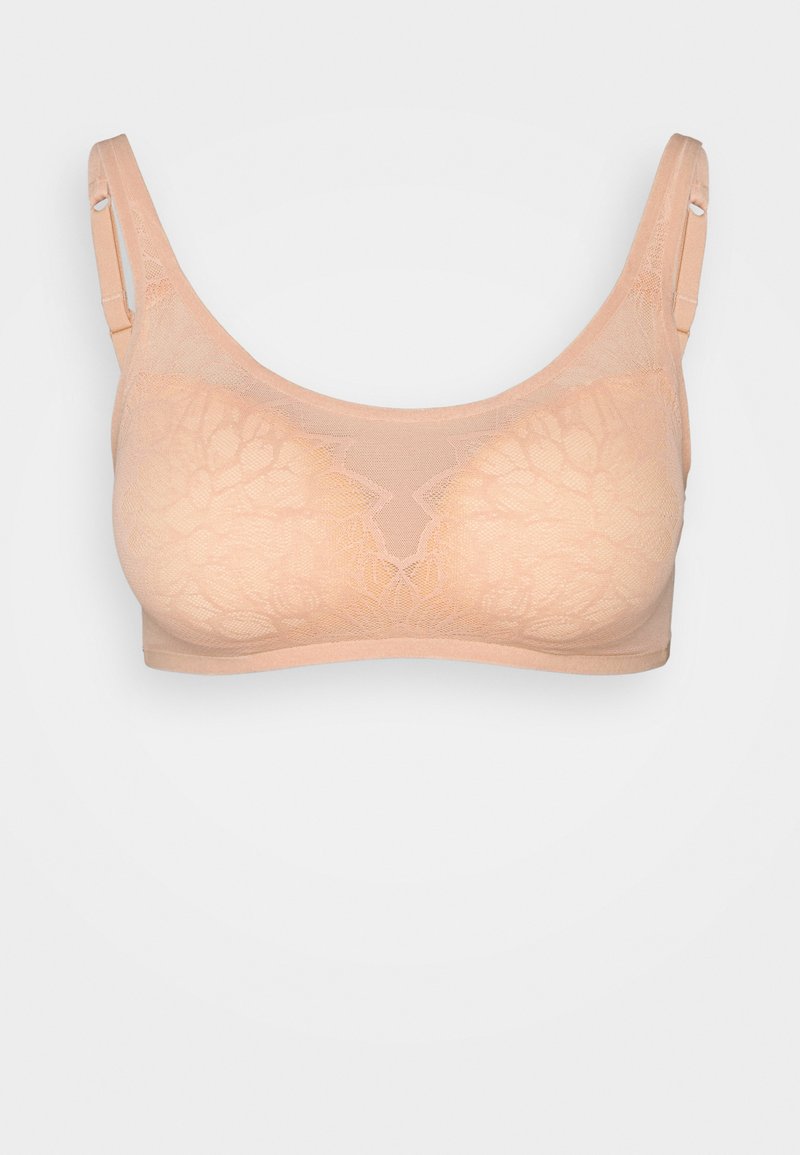 Bralette en dentelle beige avec une finition douce et texturée. Il dispose de bretelles réglables et d'un design sans couture sans matériel visible.