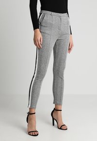 Kalhoty s šedým houndstooth vzorem a bílými bočními pruhy. Přizpůsobený střih, střední pas, přední kapsy a hladká textura.