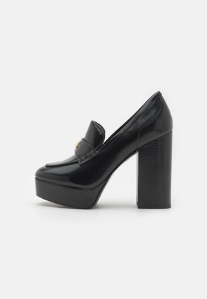 Mocassin à plateforme en cuir verni noir avec talon bloc haut et petite décoration dorée sur la bride, vu de côté.