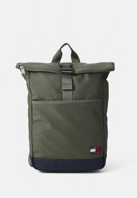 Groene rugzak met een rolbare bovenkant, gemaakt van stof, een voorvak met rits en een marineblauwe onderrand. Voorzien van een logopatch aan de onderzijde.