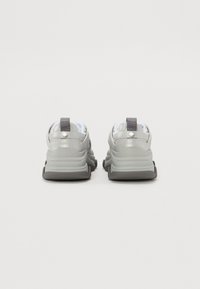 Zapatillas grises con parte superior de malla texturizada, cuello acolchado y suela de goma; presentan un acento plateado y una lengüeta trasera para facilitar el calzado.
