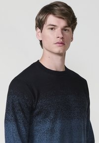 Fekete és kék gradient kötött pulóver, kerek nyakkivágással, puha tapintással és finom foltos mintával, ami a sötétről a világosra vált.