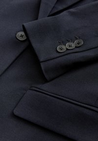 Navy blazer with a textured fabric, featuring a notch lapel, three black buttons on the cuff, and a tailored fit.