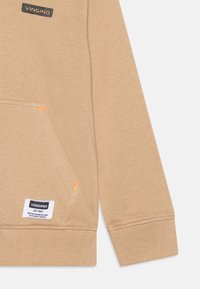 Felpa beige con finitura testurizzata, dotata di tasca a marsupio, logo "VINGINO" nero e cuciture decorative arancioni.