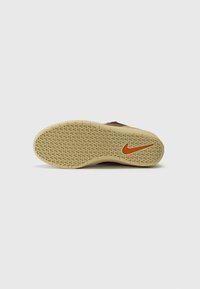 Rjava podplat Nike superg z raširjeno svetlo rjavo površino in oranžnim logotipom Nike swoosh. Ima satovje vzorčast za oprijem.