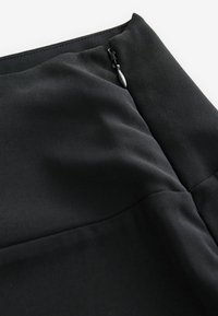 Gonna nera in tessuto morbido, con chiusura a zip in vita e cuciture per un design strutturato.