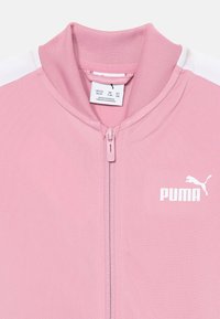 Ružičasta jakna na zip s visokim ovratnikom, teksturirana tkanina, bijeli akcenti na ramenima i bijeli Puma logo na lijevoj strani prsnog koša.