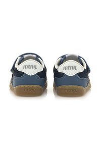 Zapatillas infantiles azules y marinas con una correa blanca y gris, tejido texturizado y suelas de goma que presentan la marca "mtng." en el talón.