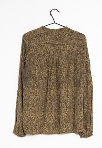 Blusa a maniche lunghe con scollo rotondo, realizzata in tessuto leggero, con una base beige e un motivo a pois neri su tutta la superficie.