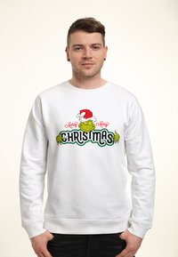 Sweatshirt bianco con un personaggio dei cartoni animati verde che indossa un cappello di Babbo Natale, con la scritta "Buon Natale" in lettere rosse e verdi.