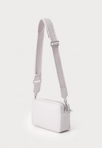 Calvin Klein rektangulær crossover-bag i myk rosa, laget av glatt materiale, med en vevd stropp med preget logo og detaljer i sølvfarge.