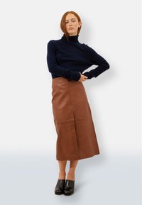 Granatowy sweter z golfem, krótki krój; brązowa skórzana spódnica midi, gładka faktura; czarne masywne obcasy. Czyste linie, minimalistyczny design.