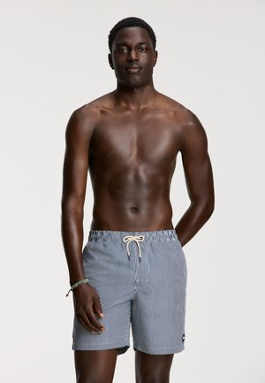 Pantaloni scurți de baie cu dungi în nuanțe de bleumarin și alb, cu șnur de ajustare, având o etichetă mică cu logo pe lateral și un material moale, ușor.