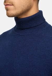 Marineblauer Rollkragenpullover aus strukturierter Strickware, mit einem hohen gerippten Kragen und einer taillierten Silhouette.