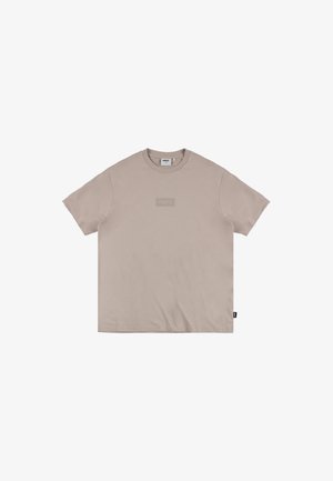 Beżowa bawełniana koszulka z okrągłym dekoltem, krótkimi rękawami, prostokątną naszywką z logo w nieco ciemniejszym odcieniu oraz metką boczną.