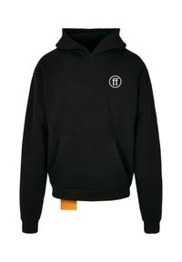 Sudadera negra con bolsillo frontal, pequeño logo circular blanco en el pecho y una etiqueta naranja visible en el dobladillo.