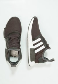 Dark gray athletic shoes with a mesh upper, white three-stripe design, textured sole, and cushioning detail. Features laces and padded collar.