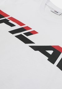 T-shirt blanc avec un grand logo FILA noir et rouge sur le devant, montrant l'encolure et l'étiquette de la marque à l'intérieur du col.