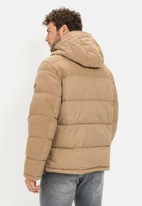 Teddyjacke in Tan mit einer Corduroy-Kapuze, gestepptem Muster und elastischen Bündchen; verfügt über einen Reißverschluss und ein Logo-Detail am Arm.