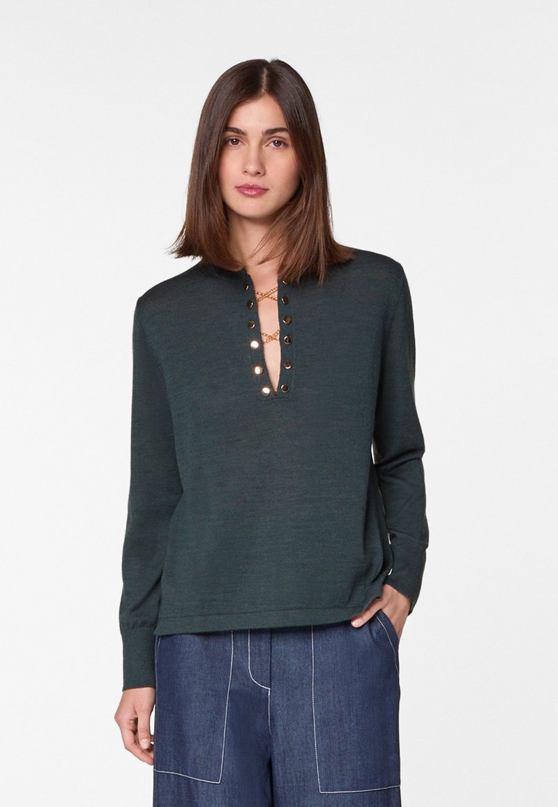 Dunkelgrüner Strickpullover mit flachem V-Ausschnitt, der goldfarbene Knöpfe entlang der Vorderseite hat. Langer Ärmel, strukturierter Stoff und eine lockere Passform.