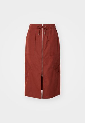Mid-length skirt in terracotta red, featuring a front zipper, elastic waistband with drawstring, and side pockets with a geometric design.