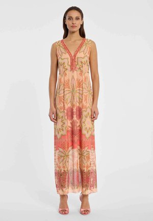 Woman wearing a sleeveless V-neck maxi dress with coral and pink floral patterns, paired with pink open-toe heels, standing against a plain background.