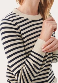 Maglione a righe con strisce orizzontali blu navy e beige, scollatura rotonda e polsini a costine; texture morbida e design aderente.