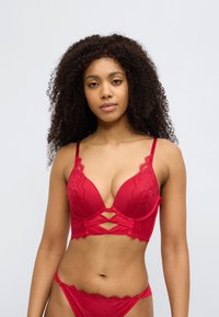 Κόκκινο δαντελένιο σουτιέν bralette με βαθύ ντεκολτέ, με διασταυρούμενες λεπτομέρειες στο μπροστινό μέρος και ρυθμιζόμενους ιμάντες. Συνοδευτικό δαντελένιο σλιπ.