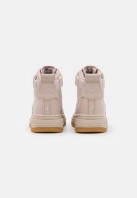 Vysoké tenisky v světle růžové kůži, s texturovaným svrškem, polstrovaným límcem a gumovou podrážkou. Detail s suchým zipem na boku.