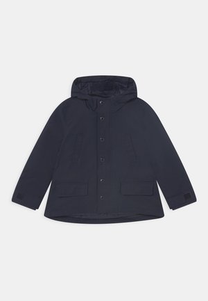 Chaqueta con capucha de color azul marino, confeccionada con material resistente al agua, que cuenta con cierre de botones, dos bolsillos delanteros y puños ajustables con velcro.