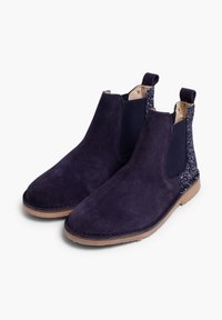 Botine din suede bleumarin cu elastic pe laterale și un detaliu texturat cu sclipici pe spate, având o talpă plată din cauciuc maro.