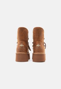 Καφέ ψεύτικες δερμάτινες μπότες αστραγάλου με χοντρό τακούνι, που διαθέτουν σχέδιο με κορδόνια και ανάγλυφο λογότυπο "REPLAY" στο πίσω μέρος.