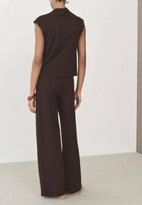 Brown sleeveless top and wide-leg pants set, made of a soft, textured material, with a relaxed fit and minimal seams.
