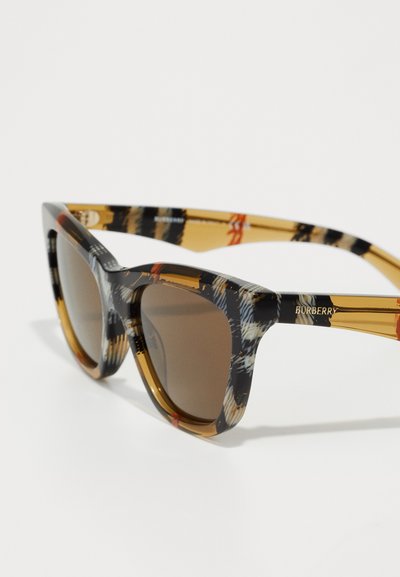 Γυαλιά ηλίου Burberry με τολμηρό σχήμα γατάκι, καφέ gradient φακούς, σχέδιο με κέλυφος χελώνας και χρυσές λεπτομέρειες στους βραχίονες.