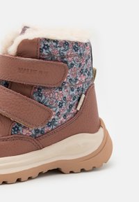 Pruun nahast saapad, millel on lillemustriga kangas, karvane vooder ja reguleeritavad Velcro rihmad. Tugev kummist konts, mis tagab hea haarduvuse.