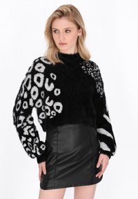 Schwarz-weißer, flauschiger Pullover mit Tierdruck-Design, ausgestattet mit Ballonärmeln, kombiniert mit einem schwarzen Leder-Minirock.