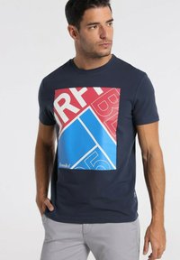 Navy blue short-sleeve t-shirt featuring a large graphic design in red and blue with bold text and geometric shapes on the front.