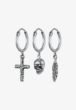 Boucles d'oreilles en argent en forme de créoles avec trois pendentifs : une croix texturée, un crâne et une feuille, chacun étant détaillé et brillant, avec des formes et des designs variés.