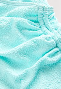 Tissu bleu clair texturé avec une ceinture élastique, présentant des plis doux et un motif en relief, moelleux.