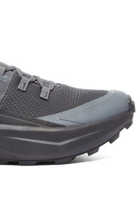 Grå löparsko med meshuppbyggnad, förstärkt tåhätta, texturerad sula och flexibelt snörningssystem. Har diskret märke på sidan.