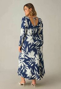 Námořnické květinové maxi šaty s dlouhými rukávy, bílým květinovým vzorem a gumičkovým pasem. Mají otevřená záda se zavazováním a volný siluetu.