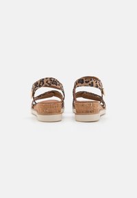 Leopard print sandals with adjustable ankle straps, cork-like heel, and a textured beige sole. Back view with dual strap design.