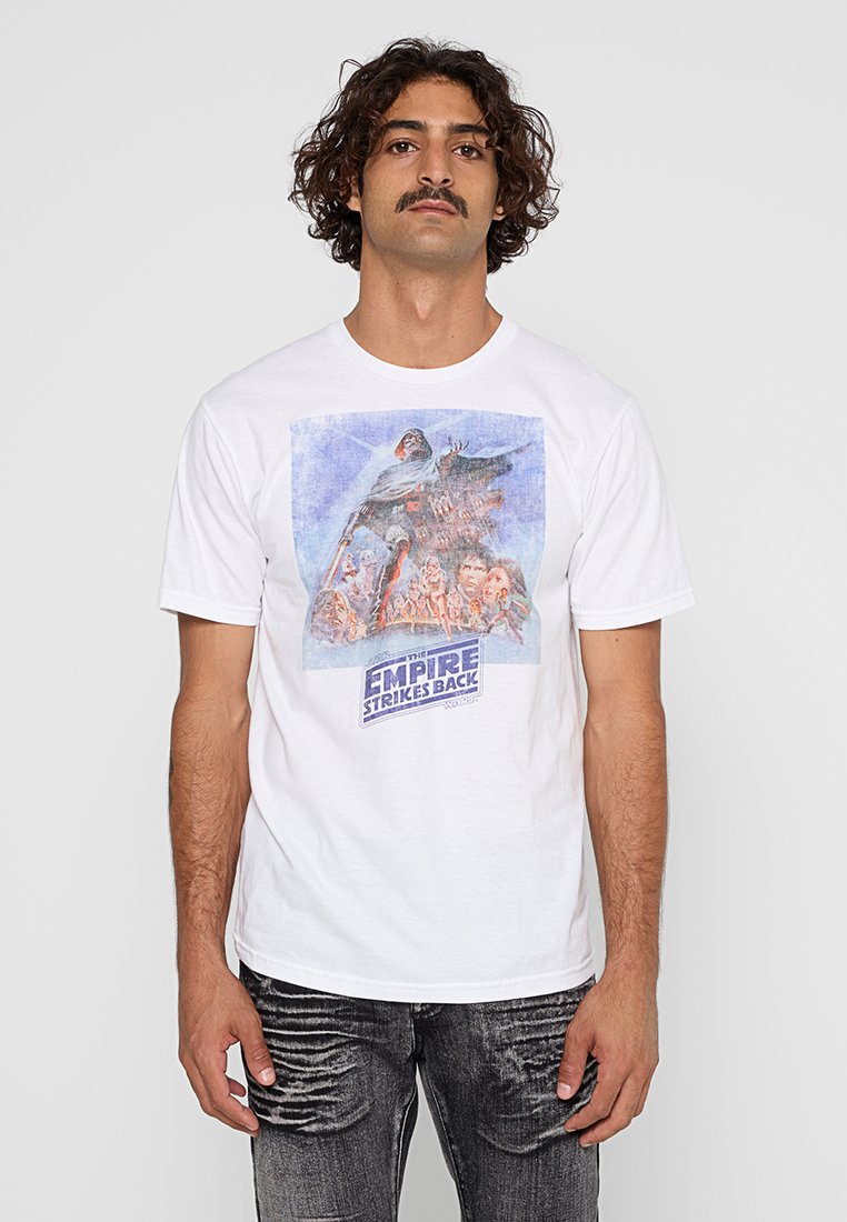 Vit bomull t-shirt med ett grafiskt tryck av "The Empire Strikes Back", som visar karaktärer i en färgglad, vintage design.